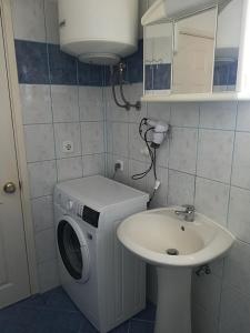 ein kleines Bad mit einer Waschmaschine und einem Waschbecken in der Unterkunft Apartment and rooms SIDRO in Petrcane
