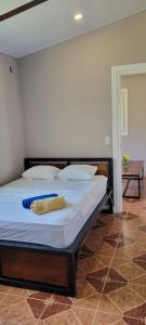 1 cama con sábanas blancas y almohadas en una habitación en Ferdinand the bull hostel, en Pedasí Town