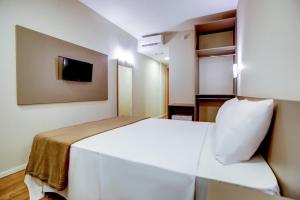 Una habitación de hotel con una cama blanca y un televisor. en Blue Tree Towers Sorriso, en Sorriso