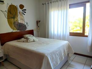 um quarto com uma cama com lençóis brancos e uma janela em Flat Sol do Ipanema em Itacaré