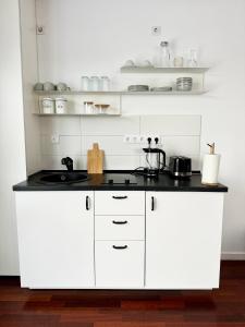 a kitchen with white cabinets and a black counter top at Central Haven Studio in Bucharest