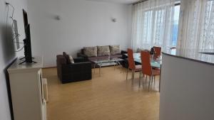 Una sala de estar con un sofá y una mesa con sillas. en Central Apartament Predeal Nr 5, en Predeal 4 fotos más