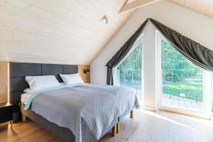una camera da letto con un letto e una grande finestra di Zachodni Wiatr - Betula a Białogóra