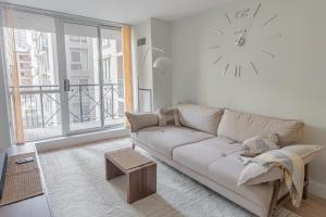 a living room with a couch and a clock on the wall at Boutique Suite in Downtown Toronto, Free Parking! in Toronto