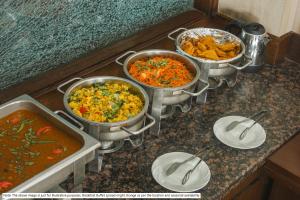 grupa trzech garnków z jedzeniem na ladzie w obiekcie Hotel Mehak Palace - Noida Sector 62 w mieście Noida