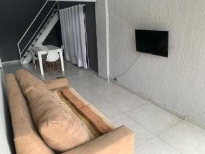 ein Wohnzimmer mit einem Sofa und einem TV an der Wand in der Unterkunft Loft Eco City 02-Espaçoso e Confortável c/ Garagem in Curitiba