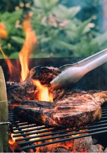 a steak being grilled on a grill with a knife at Creekside Lodge Bathpool Launceston Cornwall in Launceston