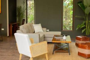 Private Modern Villa Near Resort District في Benque Viejo del Carmen: غرفة معيشة مع أريكة بيضاء وطاولة