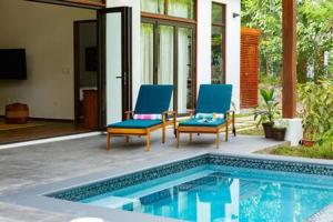 2 sillas sentadas junto a una piscina en Private Modern Villa Near Resort District en Benque Viejo del Carmen