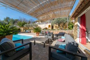 a patio with a couch and chairs and a pool at Le Chemin de la Grave - Maison avec piscine in Aups