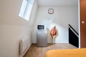 Habitación con nevera pequeña y reloj en la pared en NG SuiteHome - Lille l Roubaix Barbieux l Miln - Netflix - Wifi, en Roubaix