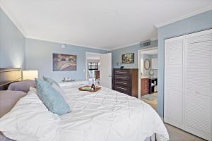 a bedroom with a large white bed with blue pillows at Olde Marco riverfront condo with pools and tennis in Marco Island