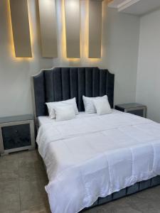 ein großes weißes Bett mit einem schwarzen Kopfteil in einem Zimmer in der Unterkunft BAHRIA HOLLIDAY HOME in Rawalpindi
