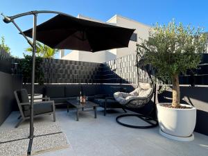 Un patio con sombrilla y sillas y una mesa. en Apartment Oris, Private Parking, Garden, en Zadar