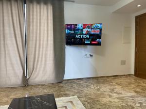 Appartement jardin de Carthage tunisia في تونس: غرفة مع تلفزيون على جدار مع ستارة
