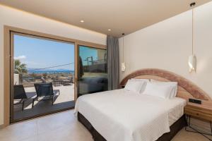 a bedroom with a bed and a balcony with a view at Cove Luxury Suites in Agia Galini