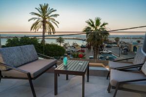 einen Balkon mit Stühlen und einem Tisch sowie Hafenblick in der Unterkunft Cove Luxury Suites in Agia Galini