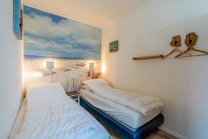 a room with two beds and a painting of a beach at Anna 222 in De Koog