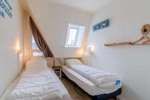 two beds in a room with two windows at Anna 222 in De Koog