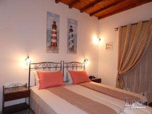 a bedroom with a bed with two orange pillows at Tinos Suites & Apartments with sea view in Agios Ioannis Tinos