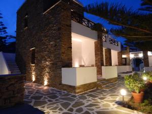 a house with a stone courtyard at night at Tinos Suites & Apartments with sea view in Agios Ioannis Tinos