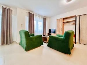 two green chairs in a living room with a television at ITHACA Σπίτι με αυτόνομη είσοδο in Thessaloniki