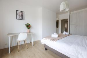 Habitación blanca con escritorio y cama en Sweet Inn - Michel Ange, en Bruselas