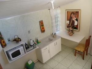 uma pequena cozinha com um micro-ondas e um lavatório em Pousada da Mari em Gramado