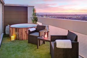 Das Penthouse - Jacuzzi - BBQ - Dachterrasse في كارلسروه: شرفة مع حوض استحمام ساخن وكرسيين وطاولة