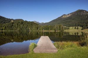 a dock on a lake with mountains in the background at Arabella Alpenhotel am Spitzingsee, a Tribute Portfolio Hotel in Spitzingsee