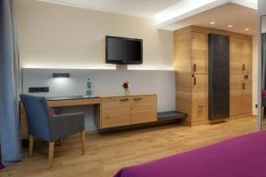 a room with a desk and a tv on a wall at Arabella Alpenhotel am Spitzingsee, a Tribute Portfolio Hotel in Spitzingsee