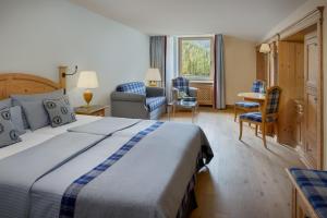 a hotel room with a bed and a table and chairs at Arabella Alpenhotel am Spitzingsee, a Tribute Portfolio Hotel in Spitzingsee