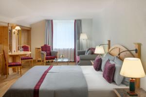 a hotel room with a bed and a living room at Arabella Alpenhotel am Spitzingsee, a Tribute Portfolio Hotel in Spitzingsee