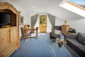 a living room with a couch and a tv at Arabella Alpenhotel am Spitzingsee, a Tribute Portfolio Hotel in Spitzingsee