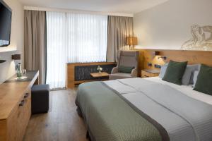 a hotel room with a large bed and a chair at Arabella Alpenhotel am Spitzingsee, a Tribute Portfolio Hotel in Spitzingsee