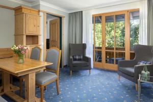 a room with a table and chairs and a window at Arabella Alpenhotel am Spitzingsee, a Tribute Portfolio Hotel in Spitzingsee