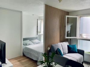 a bedroom with a bed and a couch and a mirror at Le Cocoon Quatre Pavillons Lormont in Lormont