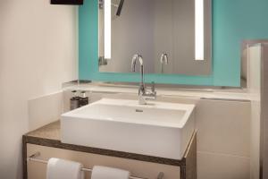 a bathroom with a white sink and a mirror at Arabella Alpenhotel am Spitzingsee, a Tribute Portfolio Hotel in Spitzingsee