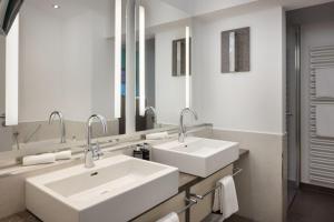 two sinks in a bathroom with two mirrors at Arabella Alpenhotel am Spitzingsee, a Tribute Portfolio Hotel in Spitzingsee