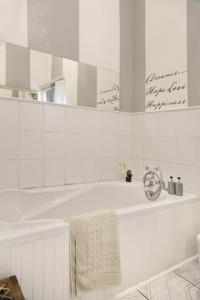 a white bathroom with a tub and a mirror at The Lighthouse Guesthouse in Colesberg