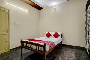 a bedroom with a bed with red pillows on it at OYO Hi 5 Apartments in Cochin