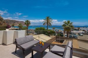 a balcony with a view of the ocean and palm trees at Cove Luxury Suites in Agia Galini