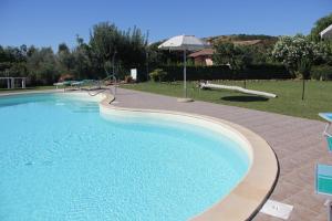 una gran piscina con una sombrilla en un patio en Agriturismo Agrifoglio en Capalbio