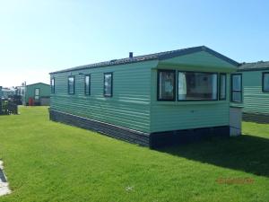 een groen huis bovenop een grasveld bij Caravan 82, Vaenol in Tywyn