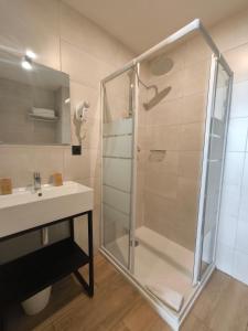 uma casa de banho com uma cabina de duche em vidro e um lavatório. em Hotel d'Ostende em Nice