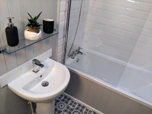 a white bathroom with a sink and a bath tub at The Old Bakery in Berwick-Upon-Tweed