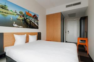 a bedroom with a white bed and a painting on the wall at easyHotel Amsterdam Zaandam in Zaandam