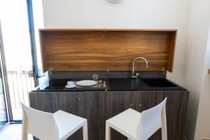 a kitchen with a sink and two white chairs at Duomo Guest House in Barletta