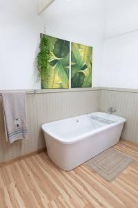 a white bath tub in a bathroom with a wooden floor at Lala Lapa Self Catering Accomodation in Nelspruit +20 photos