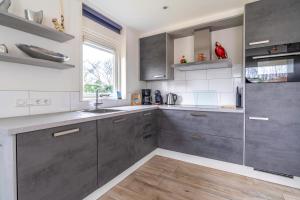 a kitchen with gray cabinets and a sink at Californiëweg 9A in De Koog